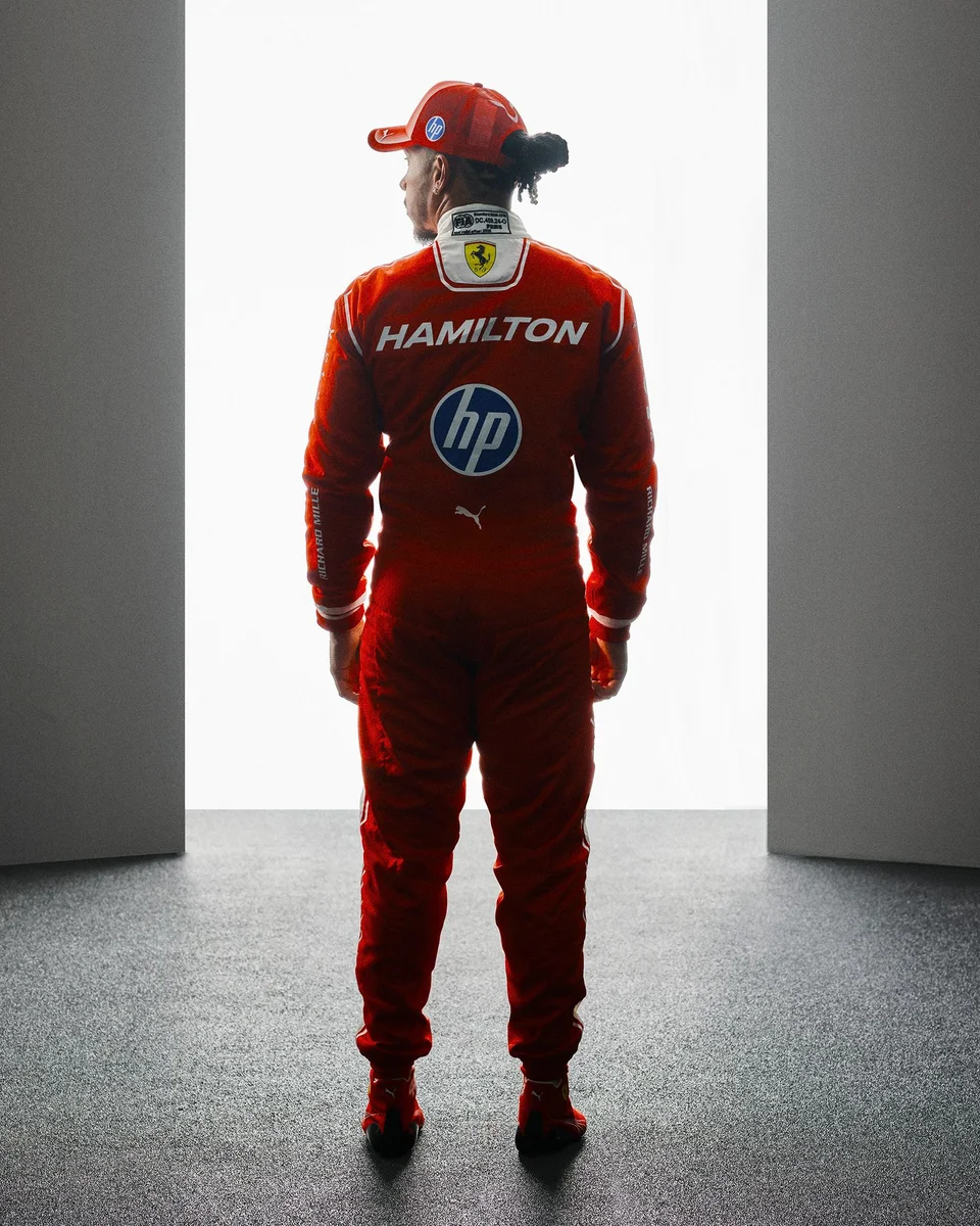 Lewis Hamilton con la tuta Ferrari 2026 ripreso di spalle in un ritratto ufficiale